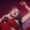 Kali Uchis in all red clothing, nail color, and red lips. She is dancing and singing with a microphone for 2021 music video for her song "telepatia"